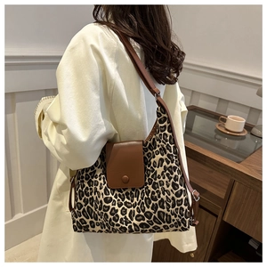 Detailed view of leopard print tote bag with brown leather flap and adjustable strap