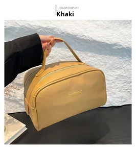 Detail of khaki pebbled leather makeup bag featuring gold logo and sturdy handle