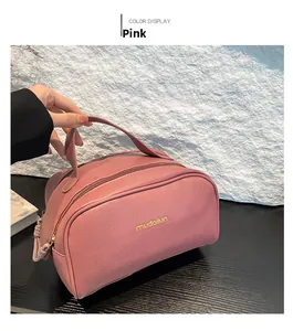 Pink lychee grain leather makeup bag with top handle and logo detail being held