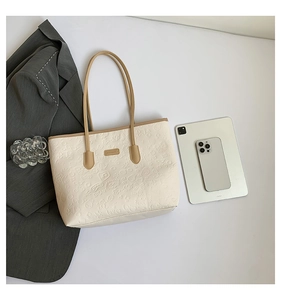 Flat lay of large embossed tote bag with cartoon patterns beside a tablet and smartphone