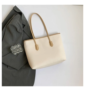 Top-down view of a spacious cream tote bag with brown handles and elegant office accessories
