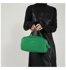 Detailed shot of green lychee leather texture and golden metal logo on the handbag