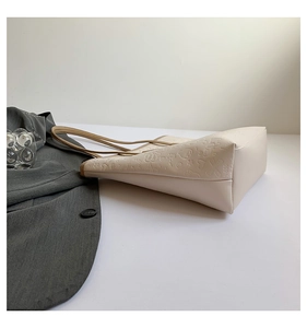 Detail view of cream tote bag featuring embossed heart and star patterns and slim strap
