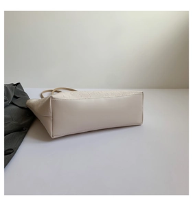 Detail of embossed 'love' pattern and flat bottom on a beige large-capacity tote bag