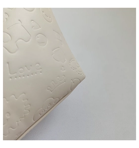 Macro detail of cream leather tote bag with embossed hearts, crowns and Love patterns