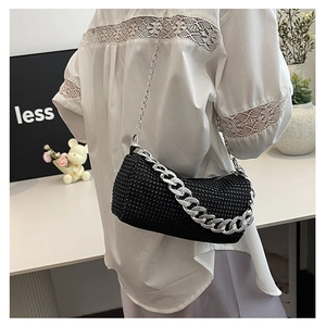 Detalle del bolso cilíndrico de diamantes negros con cadena plateada y acabado de lujo