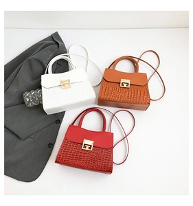 Dettaglio flat lay di borse chic con trama a coccodrillo in bianco, marrone e rosso con fibbie