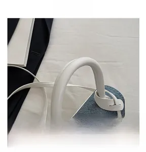 Detail of blue denim and white leather bag featuring thick round handle and fine stitching