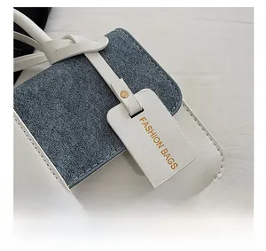 Detail of color-block crossbody bag featuring denim texture and Fashion Bags leather tag