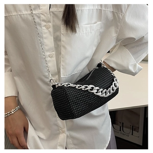 Detalle de un bolso bandolera cilíndrico negro con cristales y una cadena de plata gruesa
