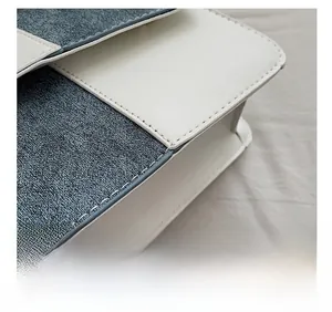 Close-up of contrast stitching on white leather and blue denim patchwork shoulder bag