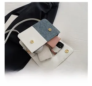 Detail showing the internal storage capacity of the blue denim and white leather crossbody bag