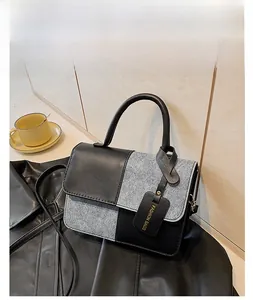 Detail of minimalist black and grey color-block crossbody bag with curved top handle