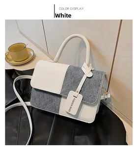 Detail of color-block crossbody bag featuring white leather and grey canvas with strap