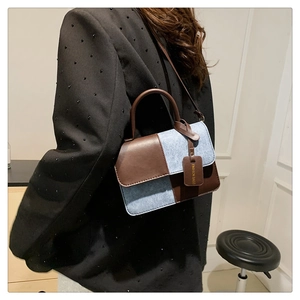 Detail view of contrast color shoulder bag featuring brown leather and blue denim texture