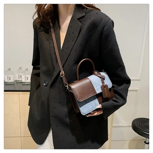 Brown leather and blue denim crossbody bag shown on model with adjustable strap