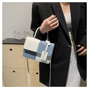 Detail of contrast stitching on beige and blue crossbody bag with fashion tag
