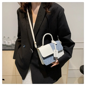 Detail of a white leather and blue denim patchwork crossbody bag with fashion tag