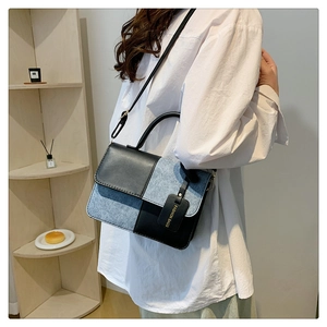 Detail of color-block crossbody bag featuring blue denim and black PU leather textures