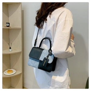 Detail of a minimalist crossbody bag featuring black leather and grey fabric contrast