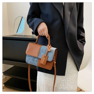 Detail of contrast stitch handbag with blue denim and brown leather on model