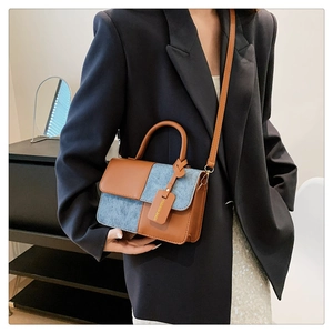 Detail of color-block flap bag with brown leather and blue denim texture and top handle