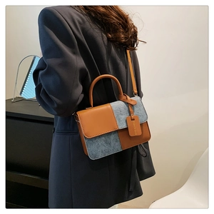 Detail of color-block crossbody bag featuring brown leather and grey denim fabric textures