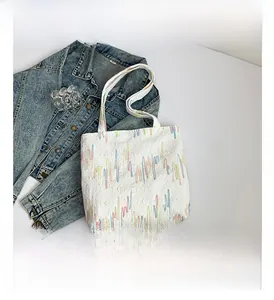 Detail of white quilted tote bag featuring multi-color wavy embroidered stripes