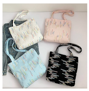 Close-up of four canvas tote bags with colorful wavy embroidery and shoulder straps