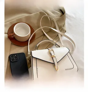 Détail du sac bandoulière blanc cassé avec boucle dorée et bords peints en noir