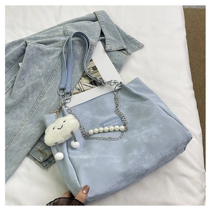 Détail du sac cabas bleu clair avec chaîne de perles et pendentif nuage en peluche