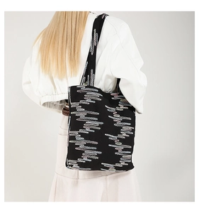 Macro detail of black tote bag featuring colorful wavy embroidery and large capacity