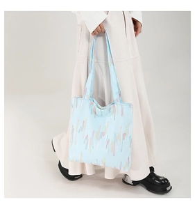 Detailed shot of large light blue canvas tote bag featuring rainbow vertical abstract stripes