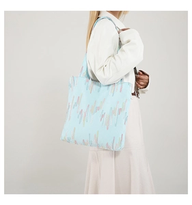 Detail of light blue tote bag featuring colorful textured embroidery on a model