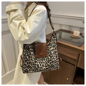Detail of leopard print canvas hobo bag with brown leather flap and adjustable strap