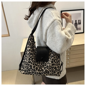 Detail of leopard print tote bag with black leather strap and buckle on white sweater