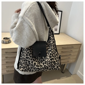 Detail of leopard print tote bag with black leather flap and adjustable shoulder strap