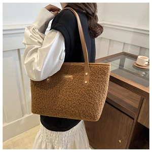 Close-up of brown plush tote bag made of lamb wool with leather straps on a model