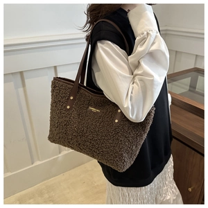 Detail view of brown faux shearling tote bag with gold studs and long leather strap