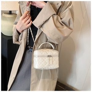 Detail of white quilted crossbody vanity bag with silver chain and top handle