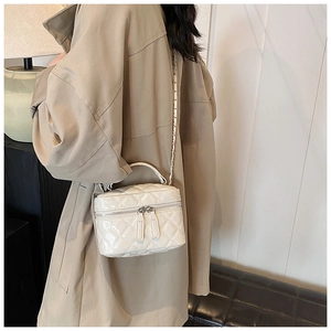 Detail of white quilted handbag featuring dual zippers and elegant metallic chain strap