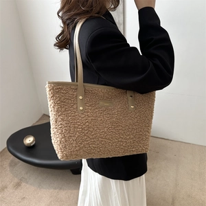Brown faux shearling tote bag with leather trim worn by model in a minimalist room