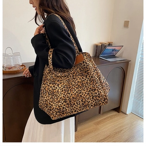 Detail of leopard print canvas tote bag with brown leather accent and long shoulder strap