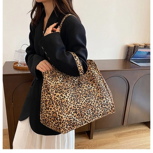 Detailed side view of the large leopard print tote bag on a wooden table with laptop