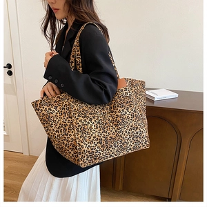 Detail of leopard print canvas tote bag with brown leather accents and sturdy straps