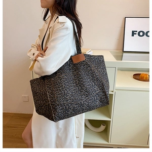 Detail of leopard print canvas tote bag with brown leather patch on an indoor model