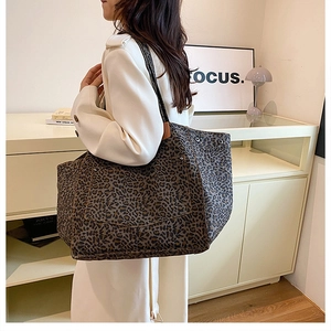 Detail of a large leopard print tote bag with an outer pocket and long shoulder strap