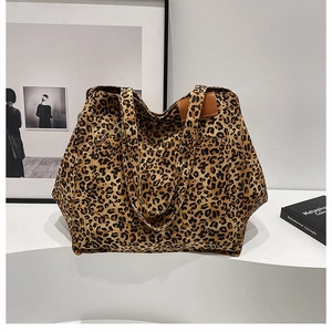 Detail of leopard print canvas tote bag featuring a leather patch and front pocket stud