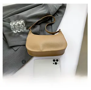 Brown lychee grain crescent bag shown next to a smartphone for size comparison