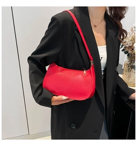 Model wearing a bright red crescent shoulder bag with golden zipper and fine grain texture